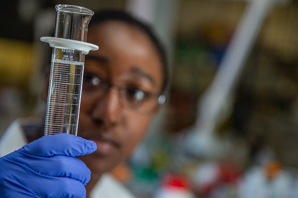 Student researcher holding graduated cylinder 